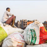 A man sits on garbage bags in west Khizrabad in South Delhi.