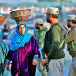 Kashmiri women walk past Indian policemen standing guard in a street in Srinagar