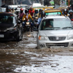 Commuters wade through a waterlogged street after heavy rainfall