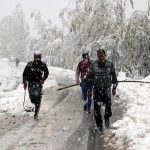 People walk through a road during the snowfall