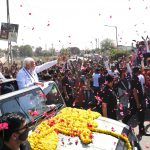 Narendra Modi waves to the people on the way from Gandhinagar to Raksha Shakti University