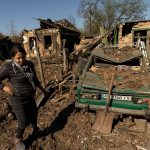 Woman stands in front of her house after a missile strike hit a residential area in Bakhmut in the Donetsk region