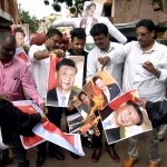 Muslim Rashtriya Manch supporters burn photographs of Pakistan Prime Minister Imran Khan and Chinese President Xi Jinping during the protest