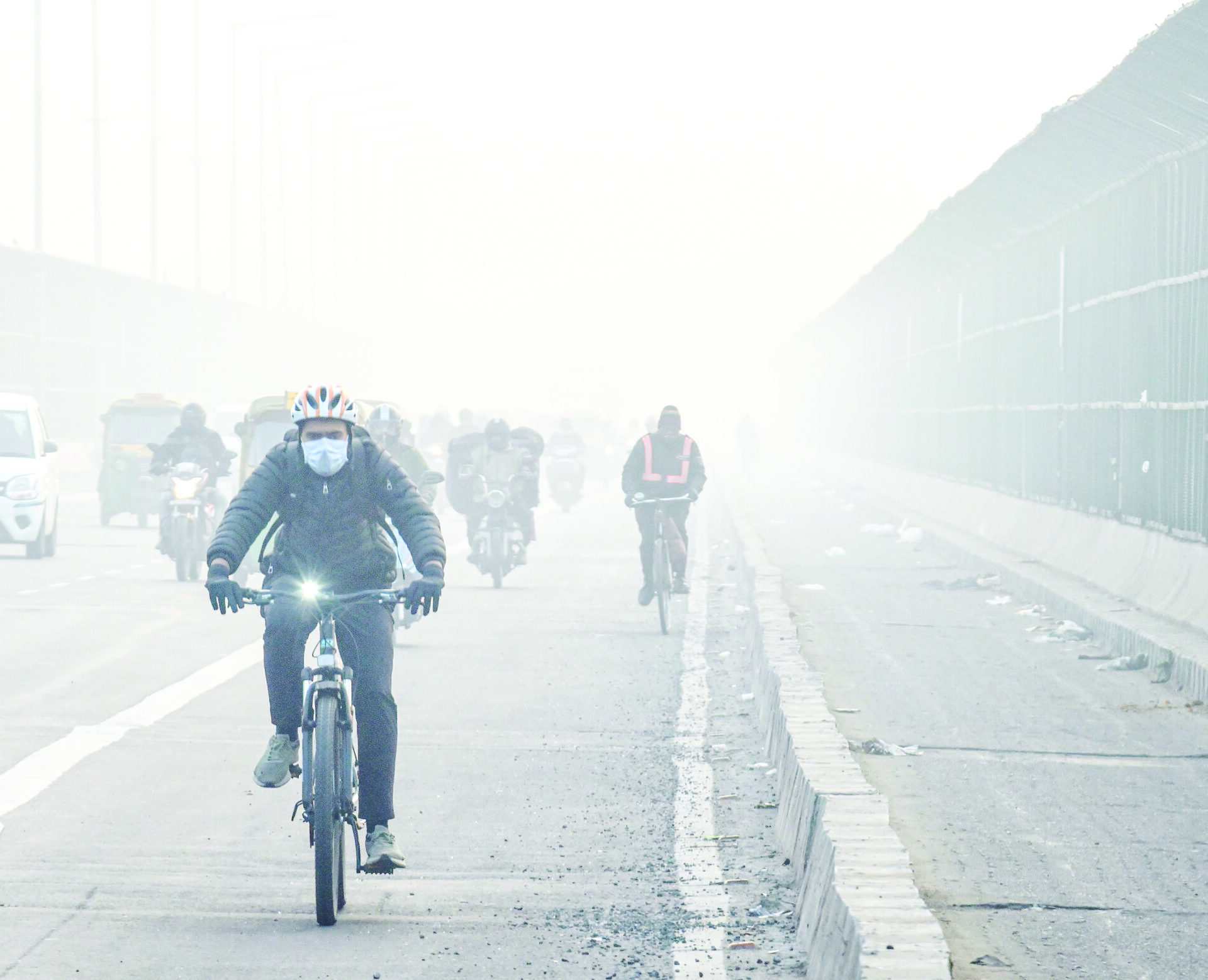 Commuters ride bicycles amid low visibility due to dense fog on a cold winter morning, in New Delhi on Saturday. (ANI)