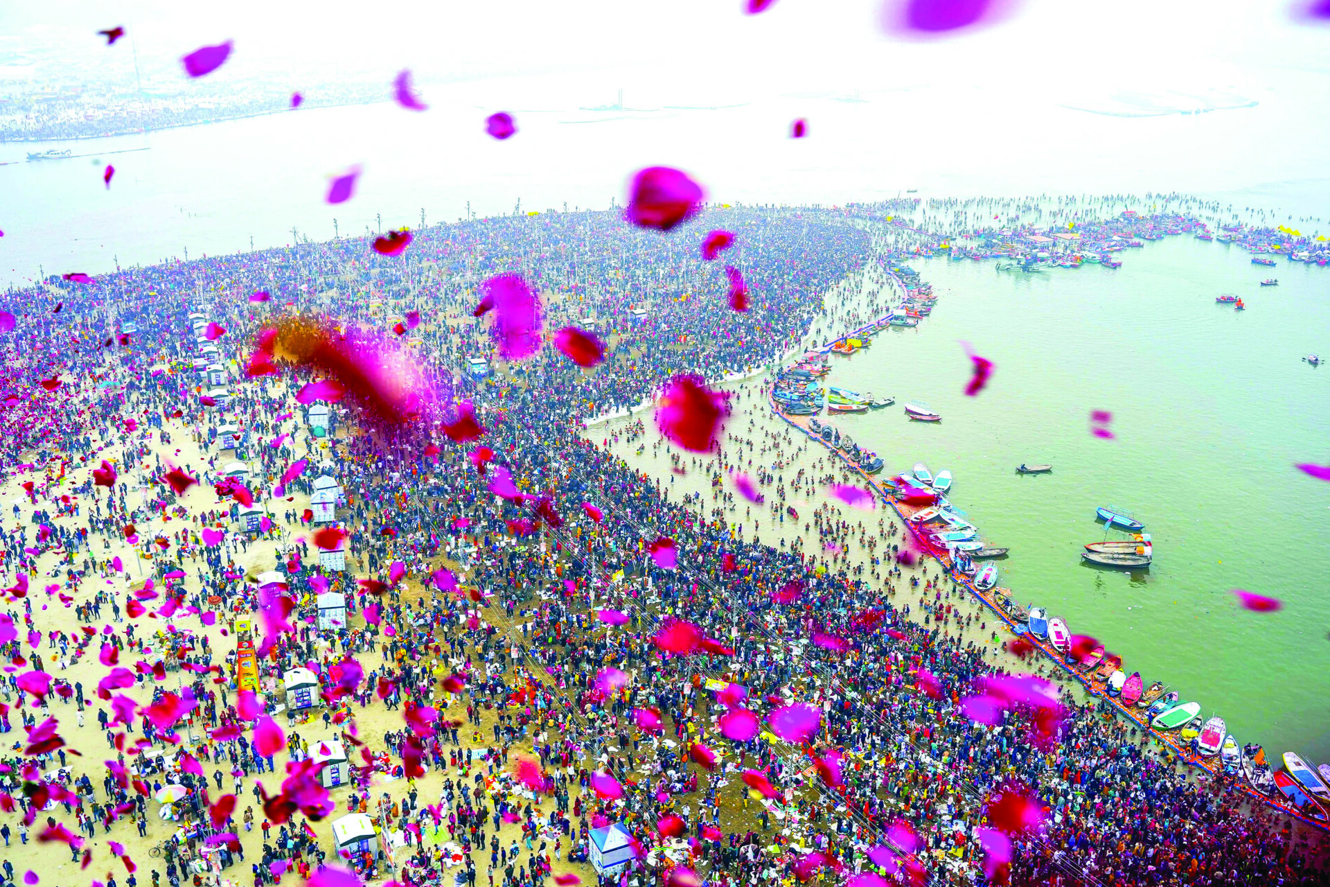 A helicopter showers flowers on devotees gathered to take a dip at Triveni Sangam on the occasion of Makar Sankranti during Maha Kumbh 2025, in Prayagraj on 14 January. ANI