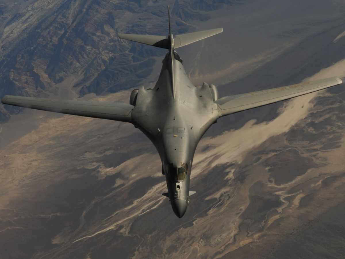 B-1B Lancer in flight over desert terrain. - Photo Gallery